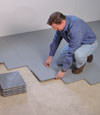 Contractors installing basement subfloor tiles and matting on a concrete basement floor in Lloydminster, Saskatchewan