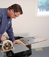 installing a waterproof vapor barrier on a basement floor to prepare for basement carpeting in a Swift Current home